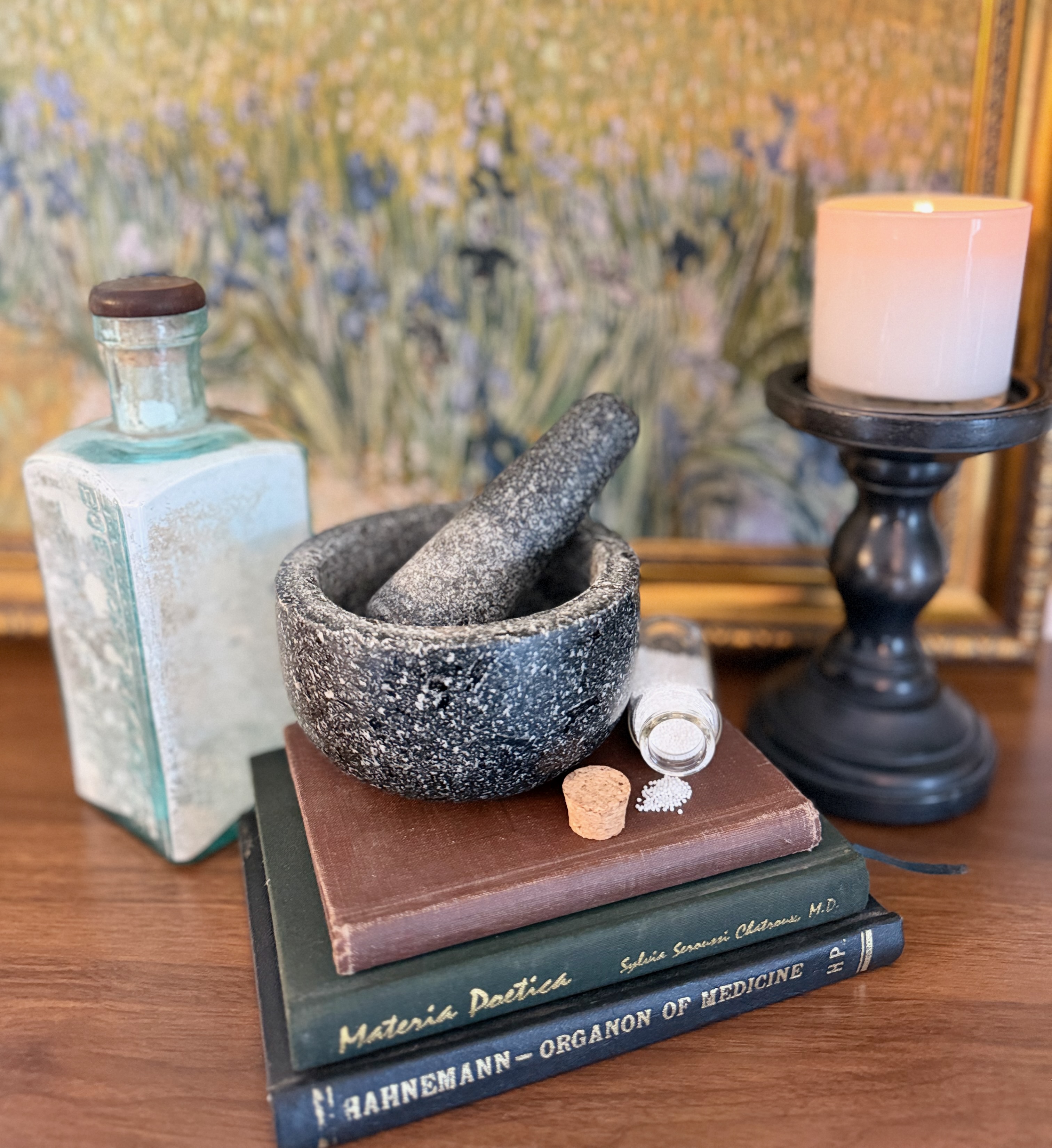 Mindy's homeopathic study collection with the Organon of Medicine, materia medica, antique Boericke and Tafel bottle, mortar and pestle, candle, and remedy vial